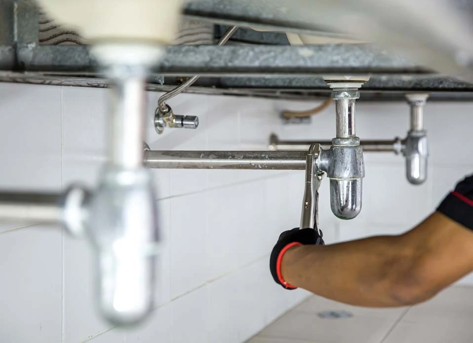 Experienced plumber using professional tools to diagnose urgent pipe failure and stop water damage, Plumber repairing leaking shutoff valve under kitchen sink in Fort Lauderdale home